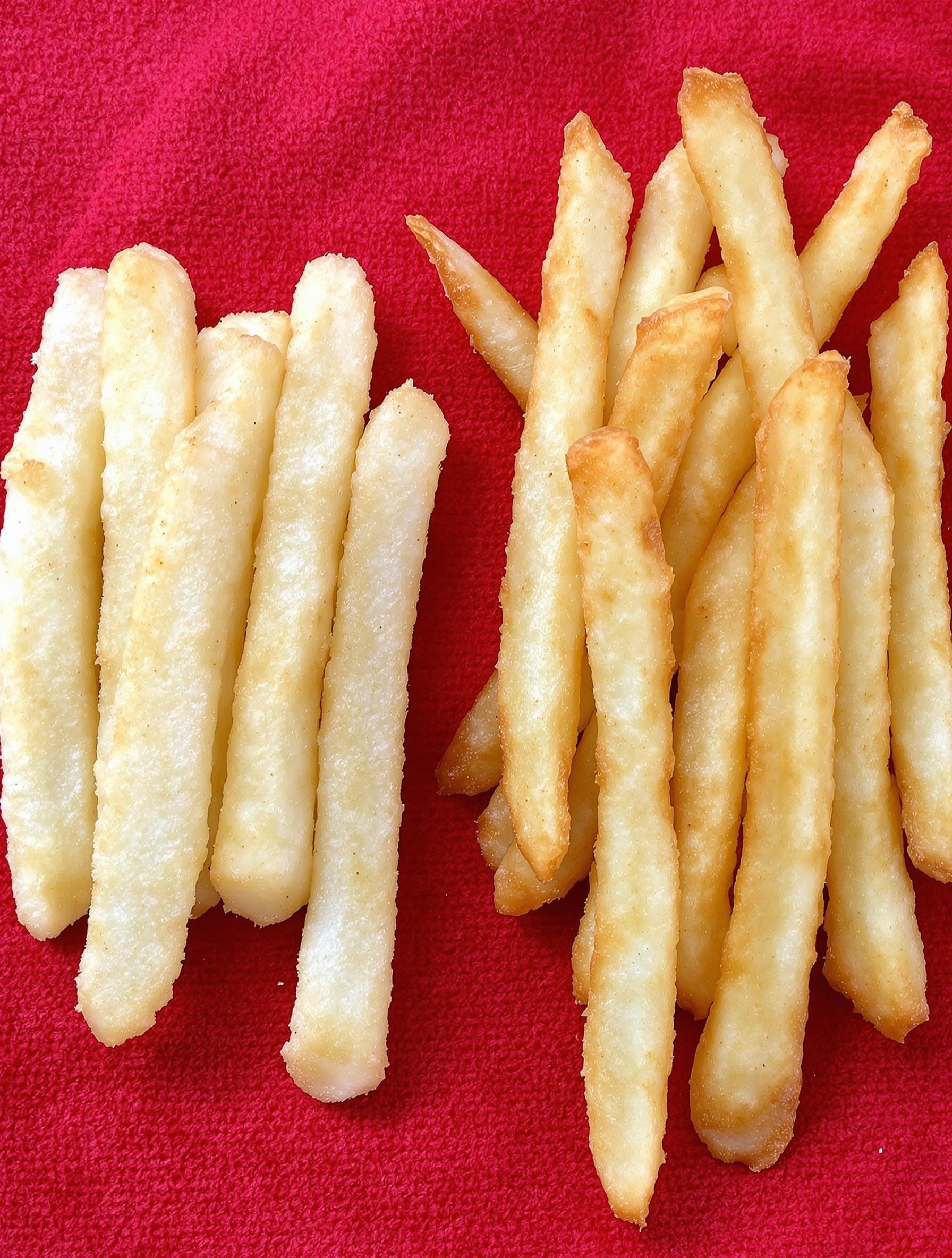 Comparaison côte à côte d’une frite palote et d’une frite dorée après reprise au Airfryer, posées sur un torchon rouge.